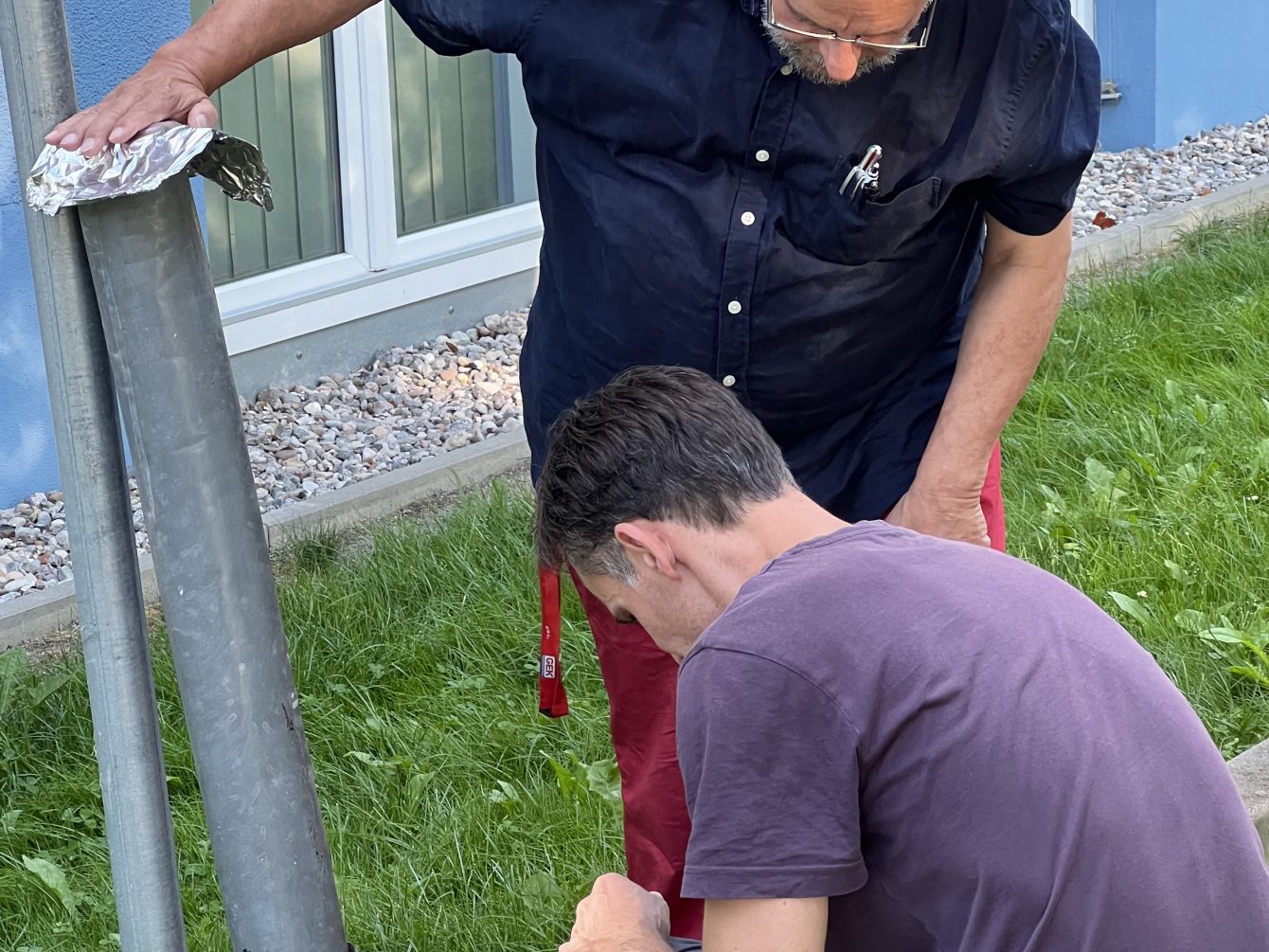 Zwei Männer messen die Temperatur an einem Lüftungsrohr